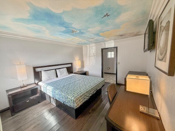 Une chambre d’hôtel comprenant un lit, des tables de chevet, un bureau et une fresque murale au plafond.