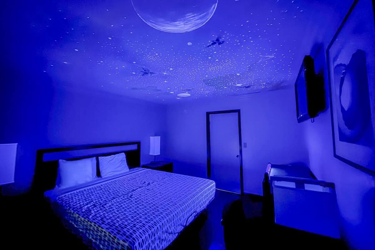 A room with a bed, a desk, and a door.