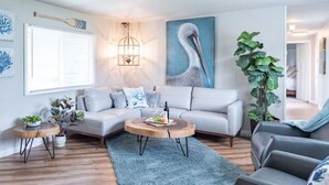 A modern living room with a light-colored sofa, a wooden coffee table, and a large potted plant. - Cozy and Stylish-Walk To The Beach - Sleeps 5 (Grayland)
