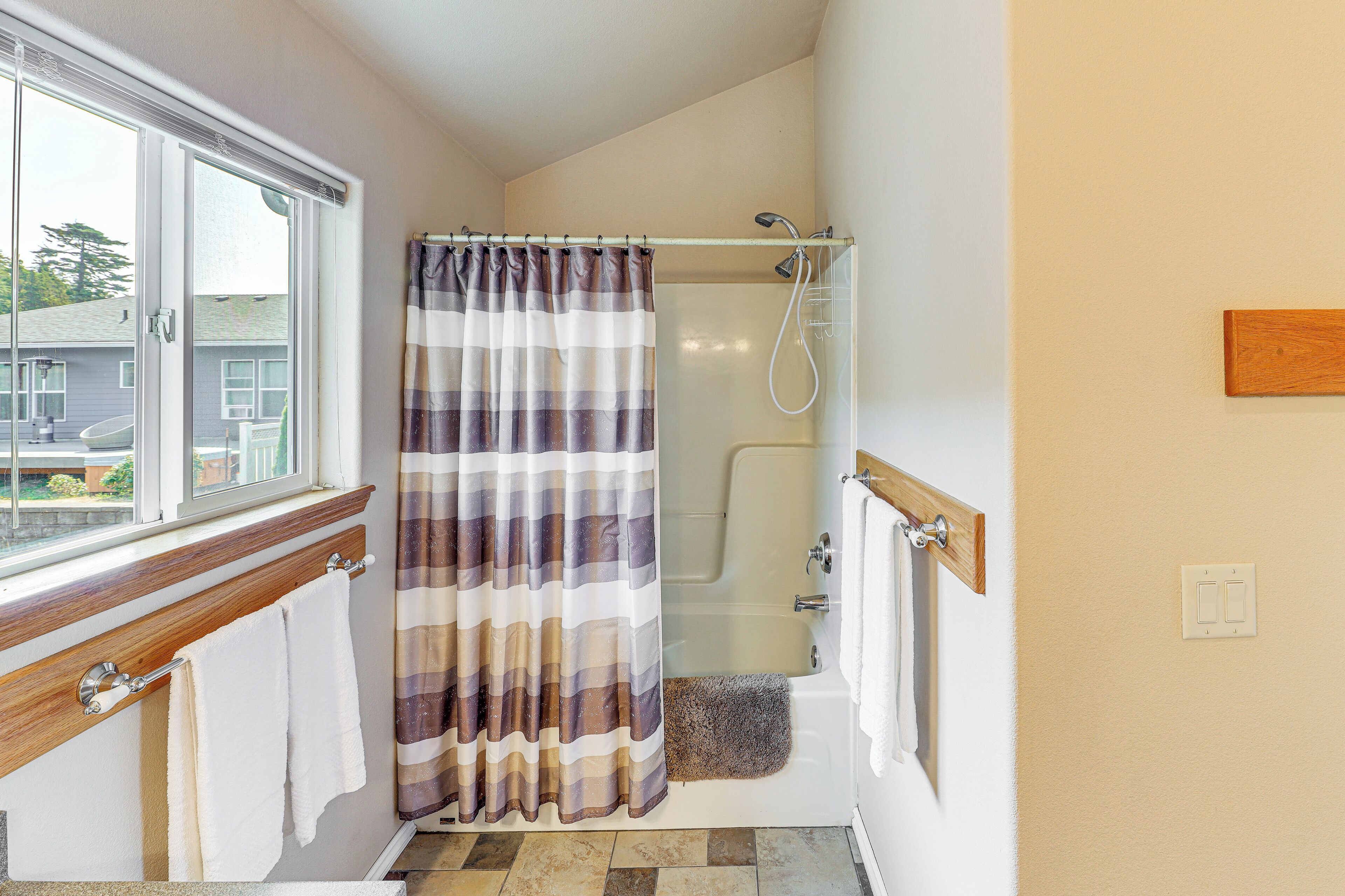 Een badkamer met een douche, een raam en een handdoekrek.
