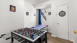 Una habitación con mesa de fútbol de mesa, dardos y una puerta con ventana.