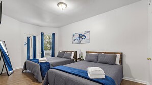 Habitación de hotel con dos camas, un cuadro y una puerta con cortinas.