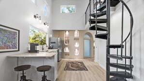 Une cuisine moderne dotée d’un îlot central, de tabourets de bar, d’un escalier en colimaçon et offrant une vue sur l’extérieur.