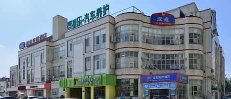 A multi-story building with commercial signage on the ground floor, including a pharmacy and a car service center.
