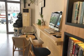 Ein Empfangsbereich mit Computer, Stühlen, einem kleinen Tisch und einem Bücherregal.