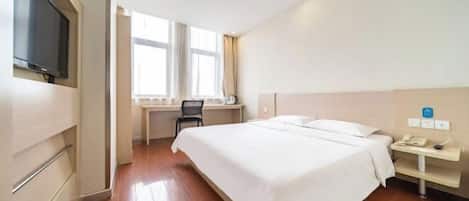 Una habitación de hotel con una cama, un escritorio, una silla, un televisor y una ventana.