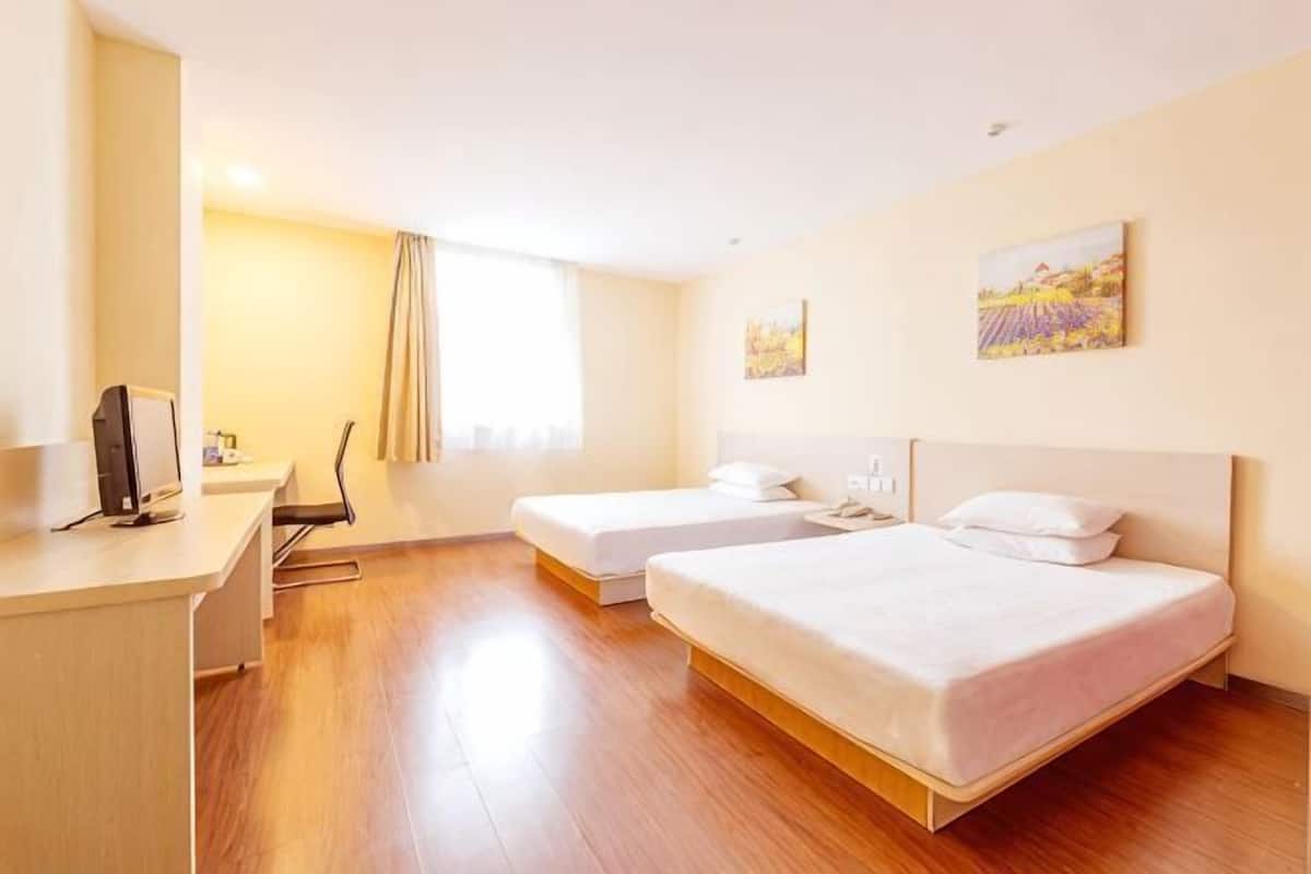 A hotel room with two beds, a desk, a chair, and a window with curtains.