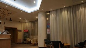 A hotel lobby with a reception desk, seating area, and a large window with curtains. - Homeinn Pebble Hotel (Shanghai Cao'an Textile Market Dingbian Road Subway Station) (Shanghai)