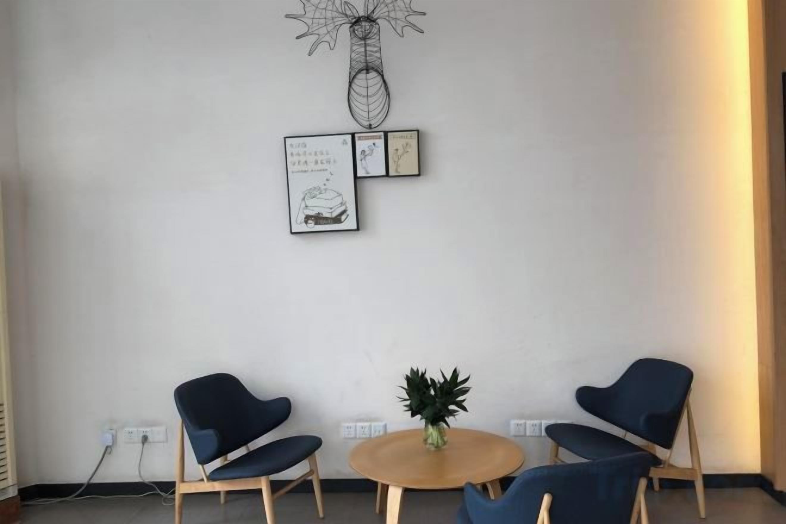 Una habitación con dos sillas, una mesita redonda y una obra de arte en la pared.