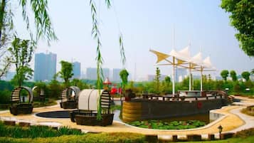 A park with a large ship-shaped structure, a circular water feature, and a pathway.