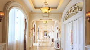 Un'imponente sala con porte ad arco, lampadari e pavimento a scacchi.