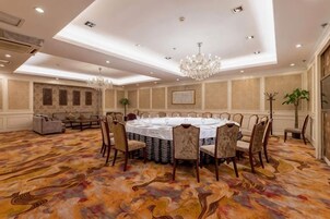 Un salón de conferencias con una mesa redonda, sillas y un candelabro.