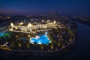 A large, illuminated hotel with multiple swimming pools and a well-lit waterfront. - Country Garden Phoenix Hotel (Changsha County)