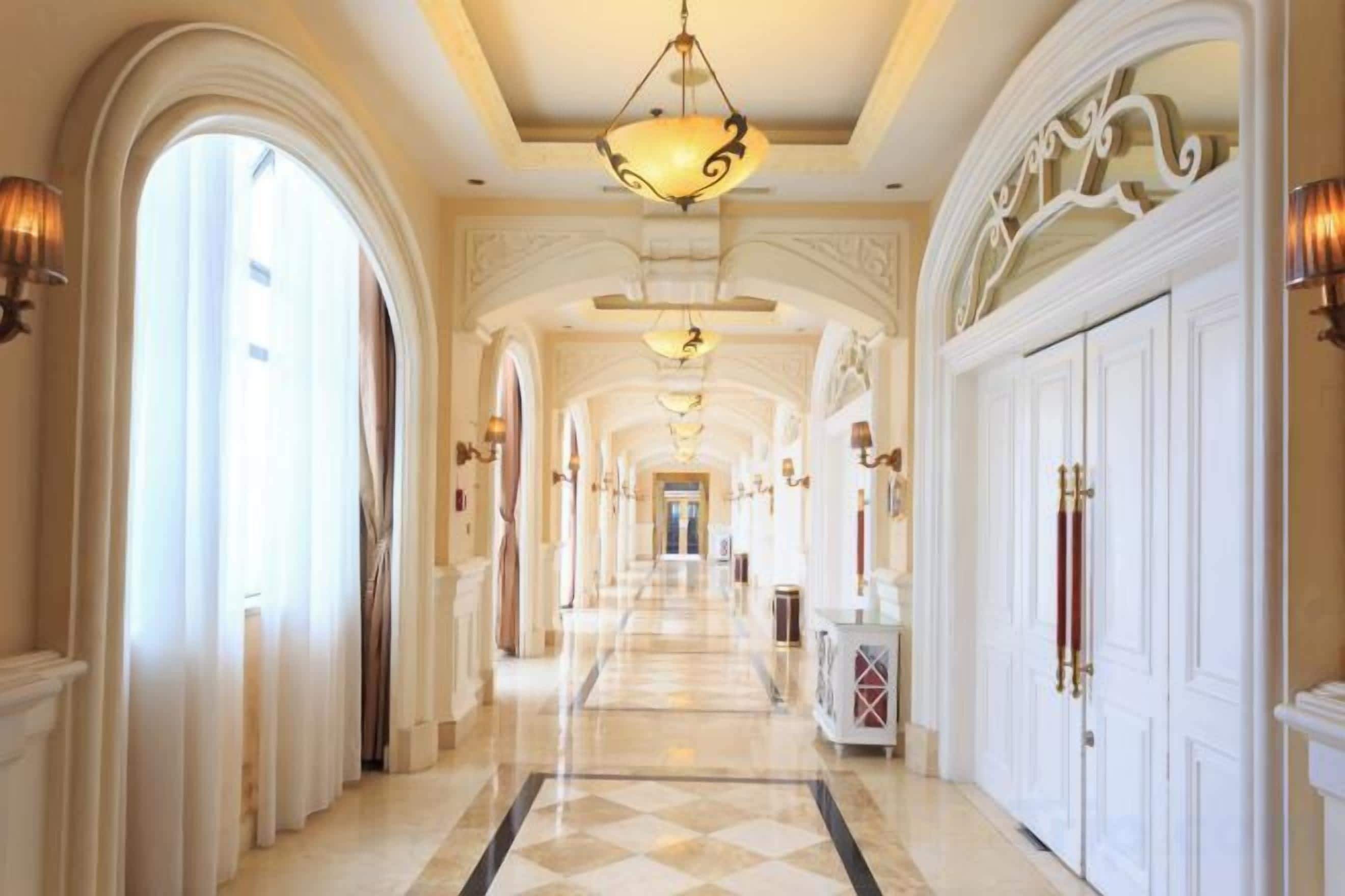 Un vaste hall d’entrée avec des plafonds en arc de cercle, des lustres et un sol à carreaux.