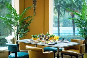A dining area with a table set for four, surrounded by chairs, and large windows offering a view of greenery. - Country Garden Phoenix Hotel (Changsha County)