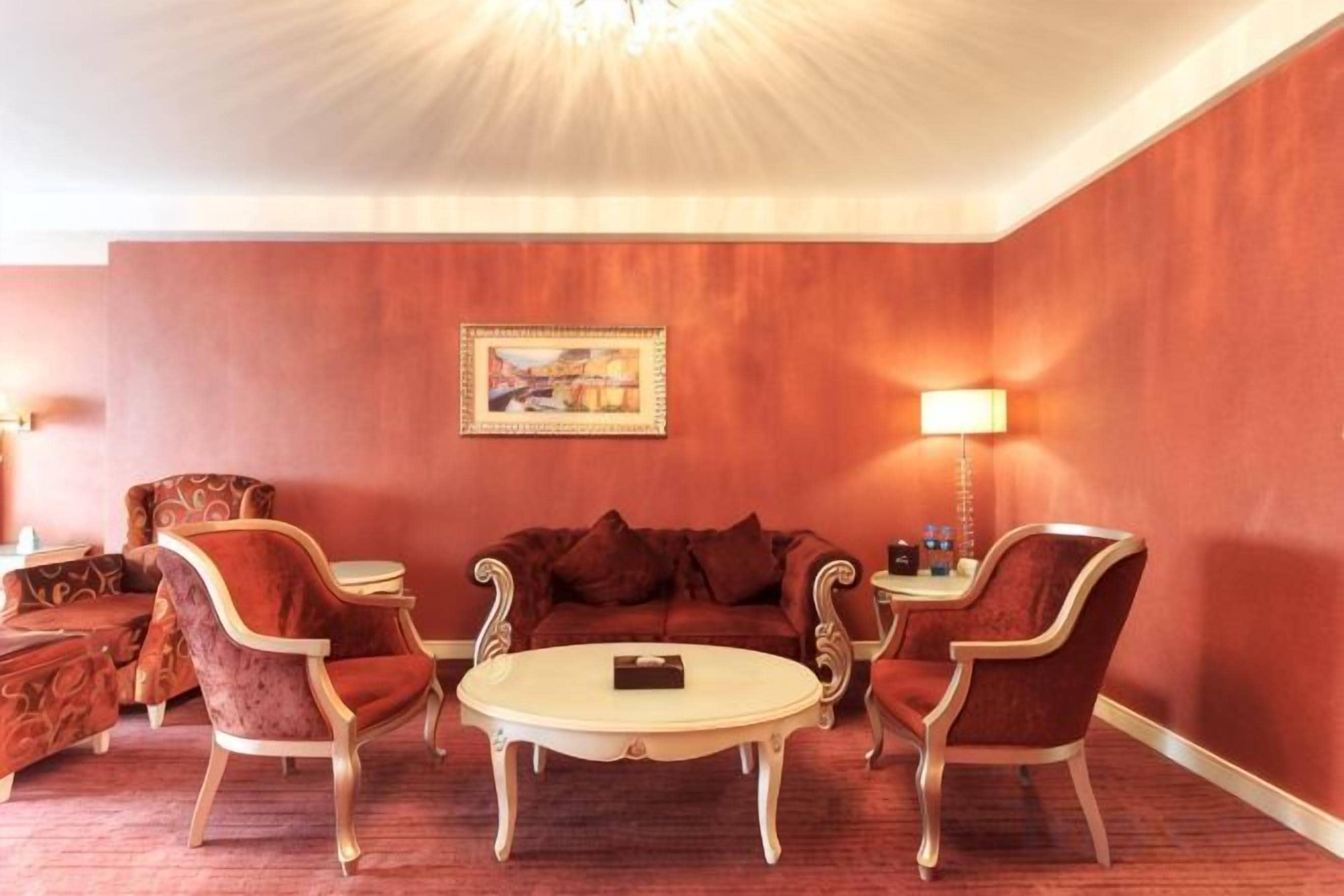 A room with a red wall, a round table, and two armchairs.