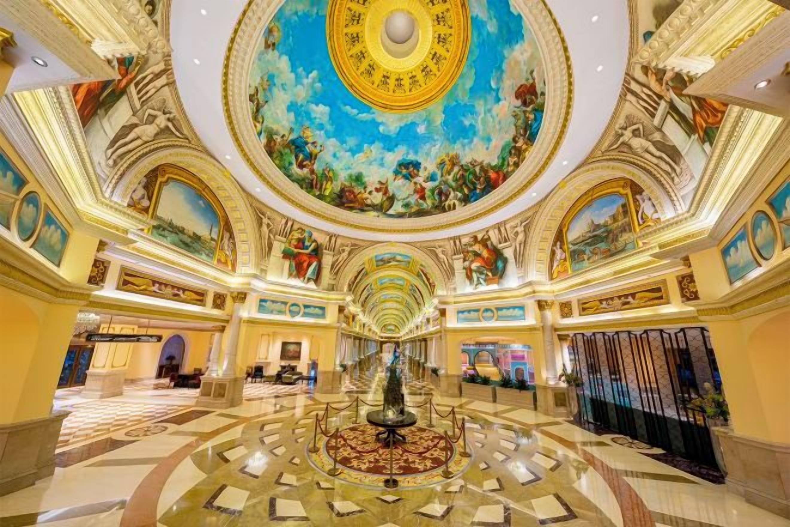 A grand lobby with a central fountain, ornate ceiling, and classical artwork.