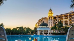 Area piscina con sedie a sdraio e un gazebo, circondata da un edificio con una cupola e balconi.