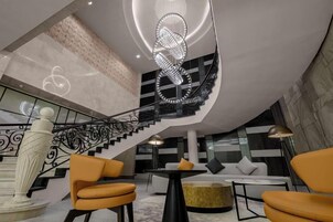 A modern interior with a staircase, seating area, and a decorative sculpture.