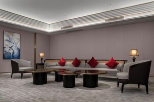 A modern lobby with a sofa set, round coffee tables, and lamps.