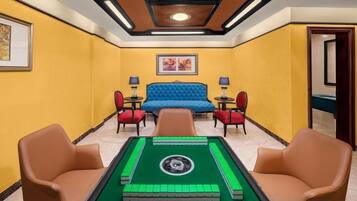 A room with a pool table, a blue sofa, and two armchairs.