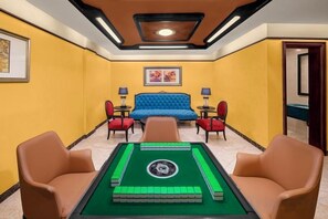 A room with a pool table, a blue sofa, and two armchairs.