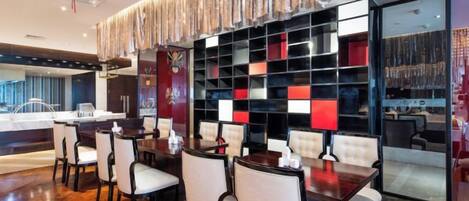 Un moderno vestíbulo de hotel con zona de bar, asientos y una pared decorativa.