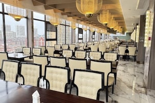 A restaurant with rows of tables and chairs, large windows, and a city view.