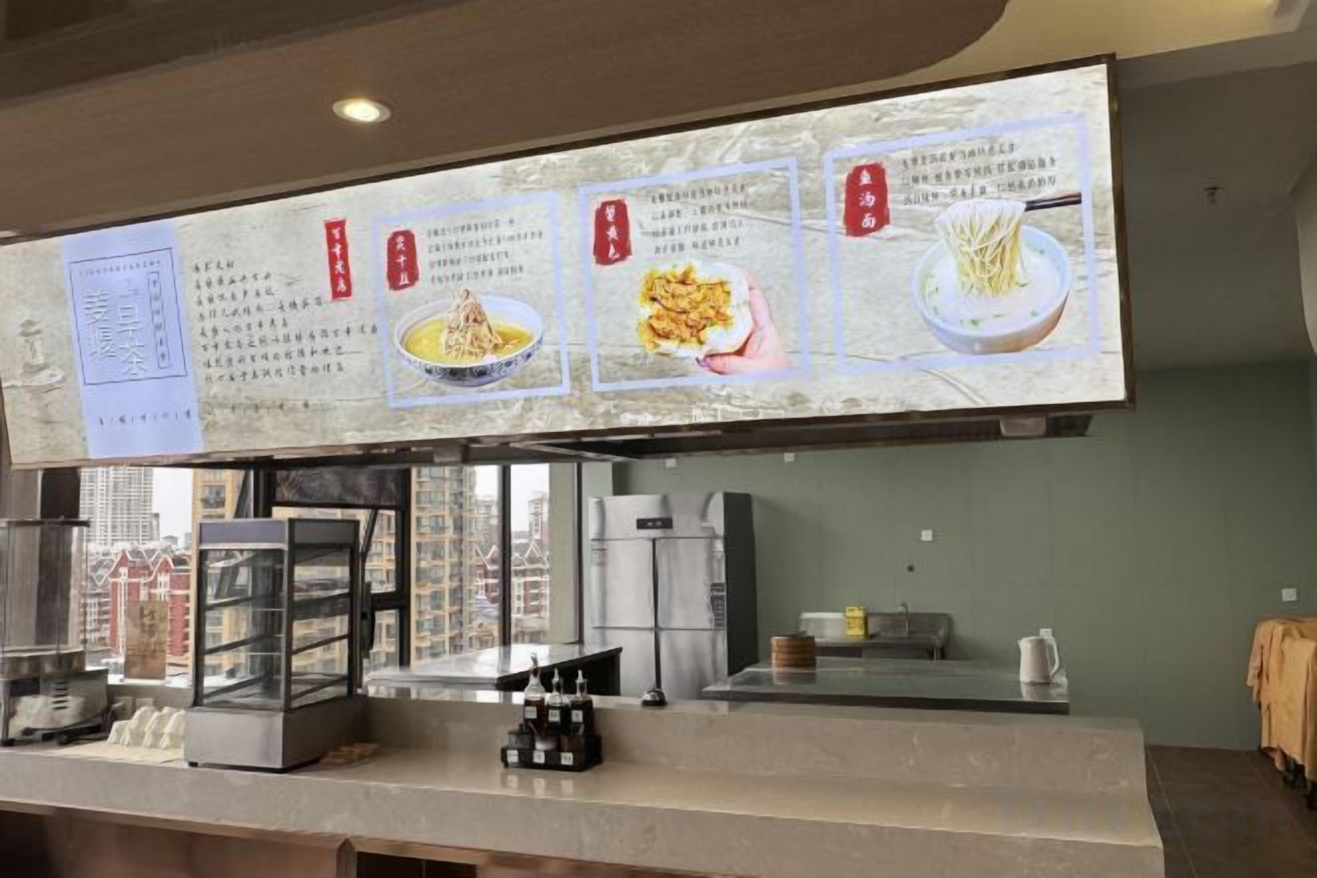 A restaurant counter with a menu display, a glass display case, and a coffee machine.