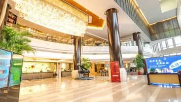 A spacious lobby with a high ceiling, large columns, and a digital information kiosk.