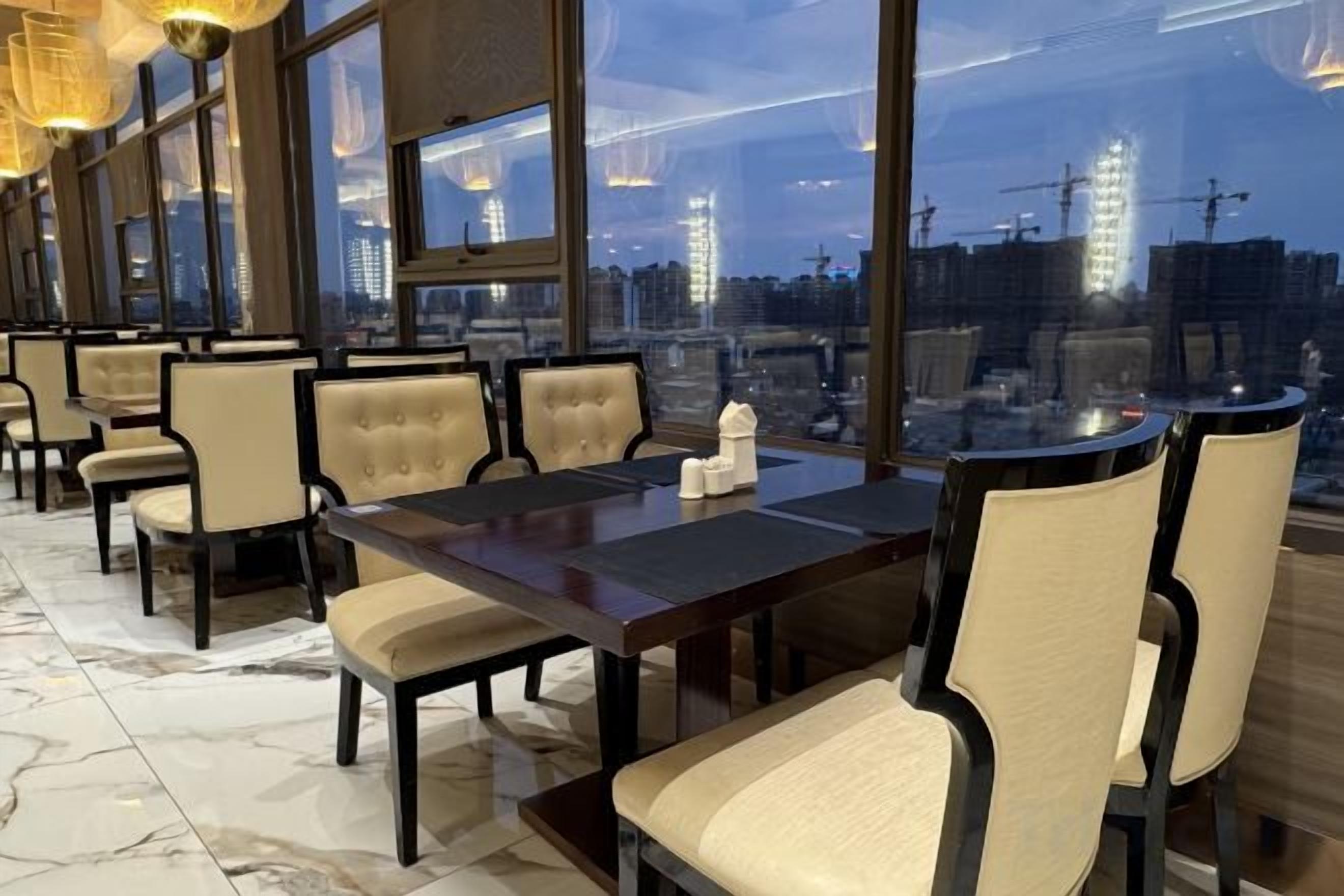 A conference room with a large table and chairs, large windows with a city view, and a marble floor.