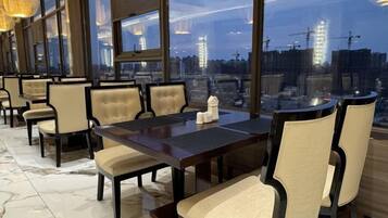 A conference room with a large table and chairs, large windows with a city view, and a marble floor.