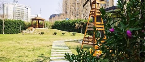 Un jardín con un sendero de piedra serpenteante, una escalera de madera y un mirador.