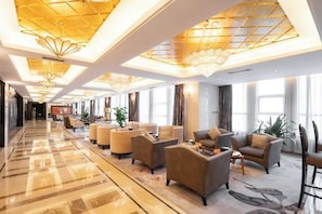 A hotel lobby with a long corridor, seating area with sofas and chairs, and a large chandelier. - Jiangyan Hotel (Taizhou)