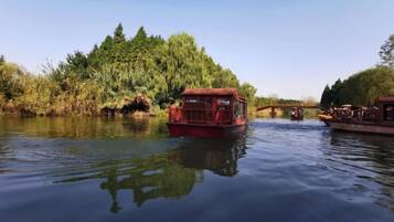 A river with a red boat and a bridge in the background.