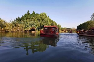 A river with a red boat and a bridge in the background.