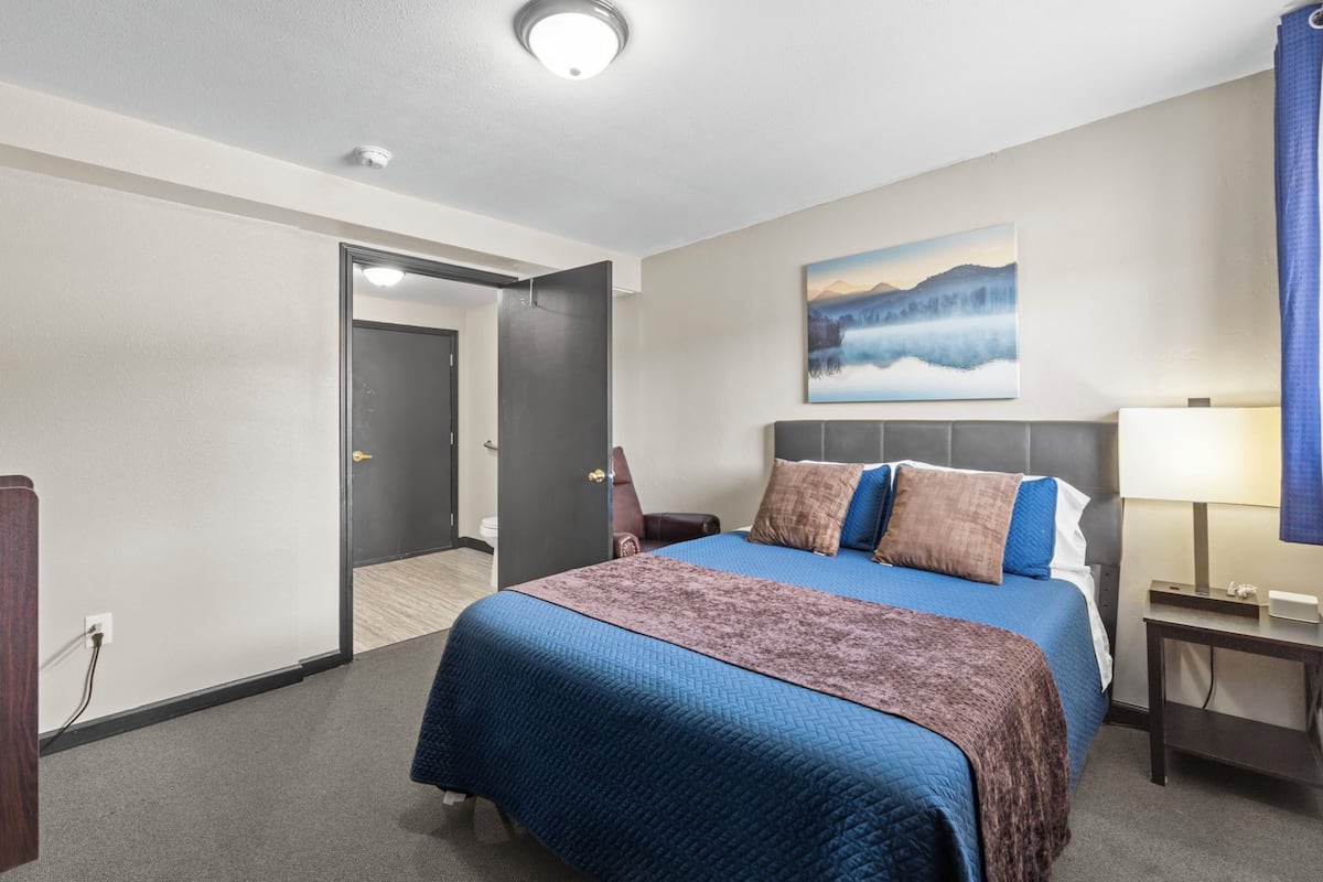 Ein Hotelzimmer mit einem großen Bett, einem Gemälde an der Wand und einem Schreibtisch mit Lampe.