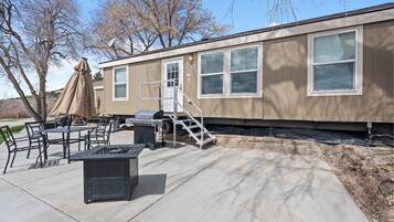 A mobile home with a patio area, outdoor furniture, and a grill.
