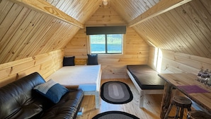 A cozy attic bedroom with a bed, a leather sofa, a dining table, and a ceiling fan. - Lost Trail Resort (Lava Hot Springs)