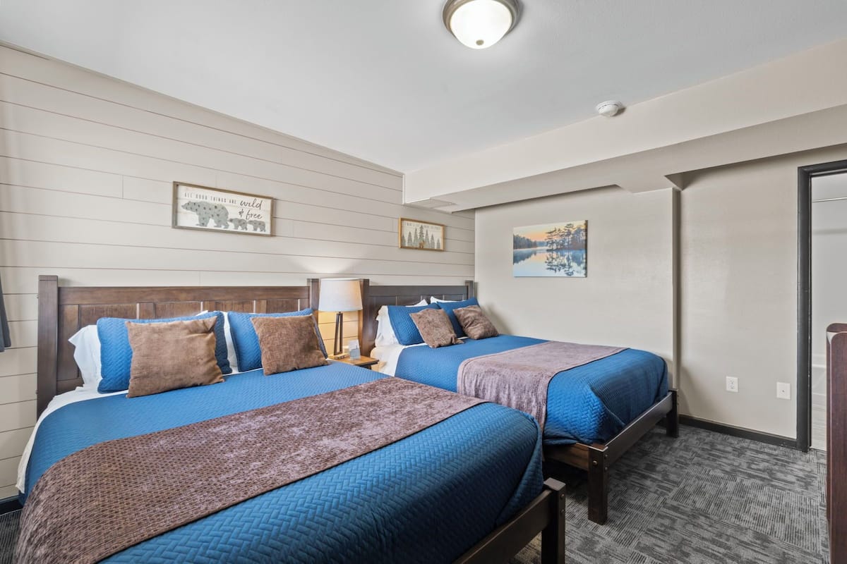 Ein Hotelzimmer mit zwei Betten, Holz-Kopfteilen und einem großen Fenster.