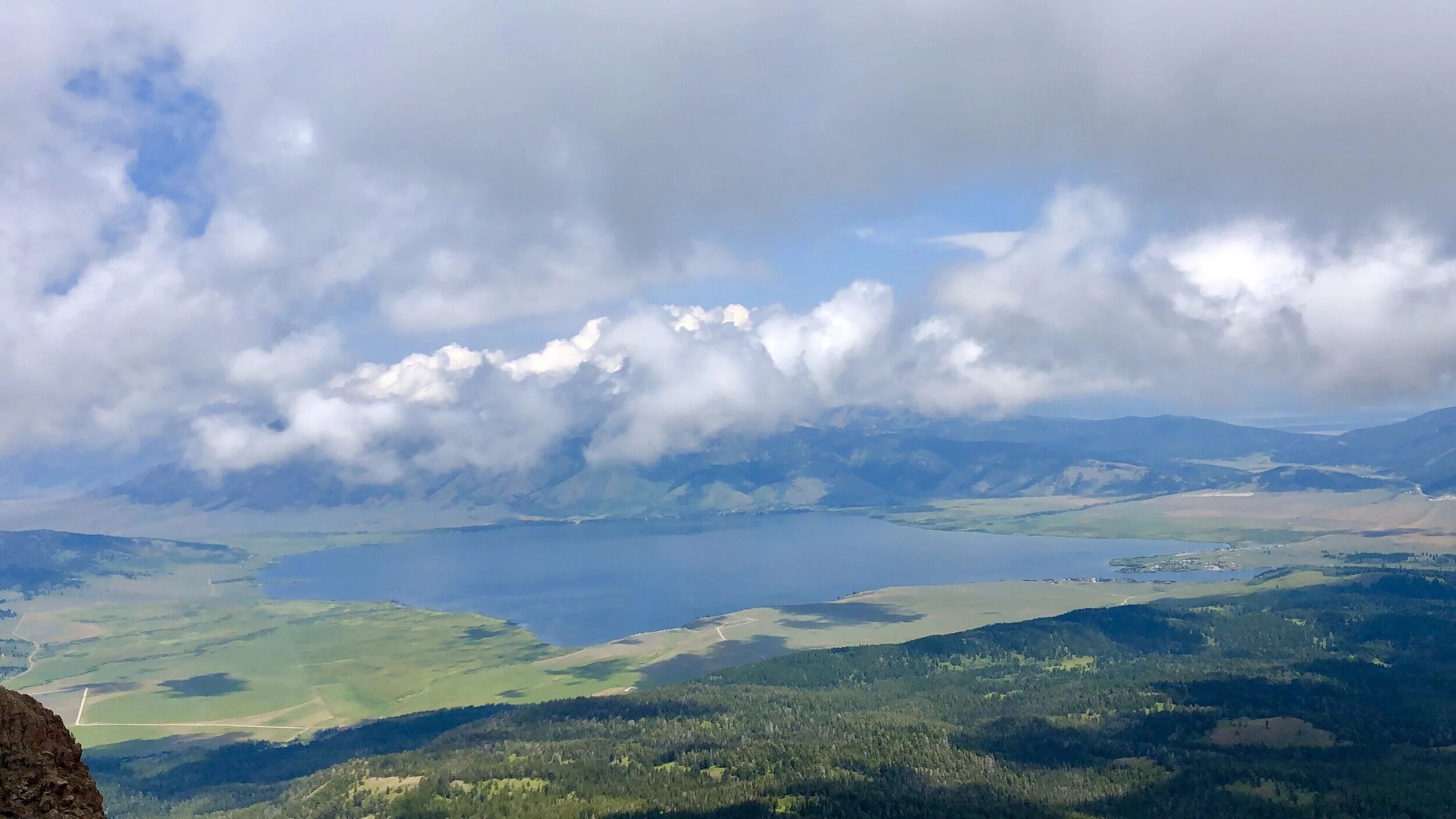 Een weids uitzicht over een meer, omringd door bergen en bossen.