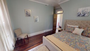 A bedroom with a large bed, a chair, and two paintings on the wall. - Historic Home in Nelsonville OH near Hocking hills (Nelsonville)