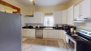 A kitchen with white cabinets, a stainless steel refrigerator, a built-in oven, and a coffee maker. - Historic Home in Nelsonville OH near Hocking hills (Nelsonville)