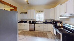 A kitchen with white cabinets, a stainless steel refrigerator, a built-in oven, and a coffee maker. - Historic Home in Nelsonville OH near Hocking hills (Nelsonville)