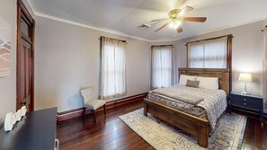 A bedroom with a wooden bed, a ceiling fan, and a nightstand with a lamp. - Historic Home in Nelsonville OH near Hocking hills (Nelsonville)