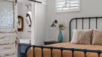 Un dormitorio con cama, mesita de noche, lámpara y una lámpara de araña decorativa.