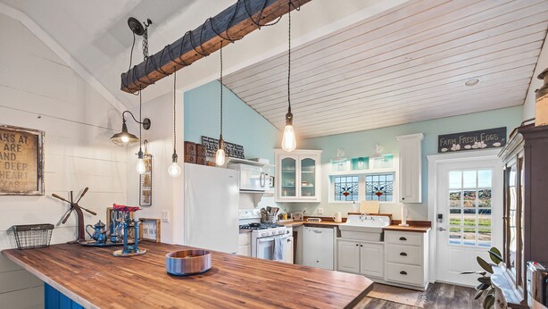 Una cocina con una isla de madera, armarios azules y diseño de estilo campestre.