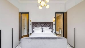 Una habitación de hotel moderna con una cama grande, una araña y suelo de mármol.