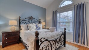 A bedroom with a bed, nightstands, a window with curtains, and a view of the outside. - Walk to the Beach with Pool and Game Room (Myrtle Beach)