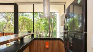 Eine moderne Küche mit großem Fenster, einem Edelstahlkühlschrank und einer Holz Arbeitsplatte.
